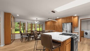 Une cuisine moderne avec des meubles en bois, un îlot central et un coin repas avec des chaises.