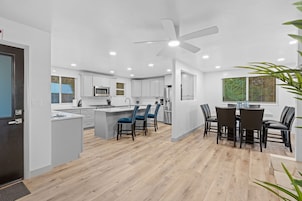 A modern kitchen with white cabinets, a central island, and blue bar stools.