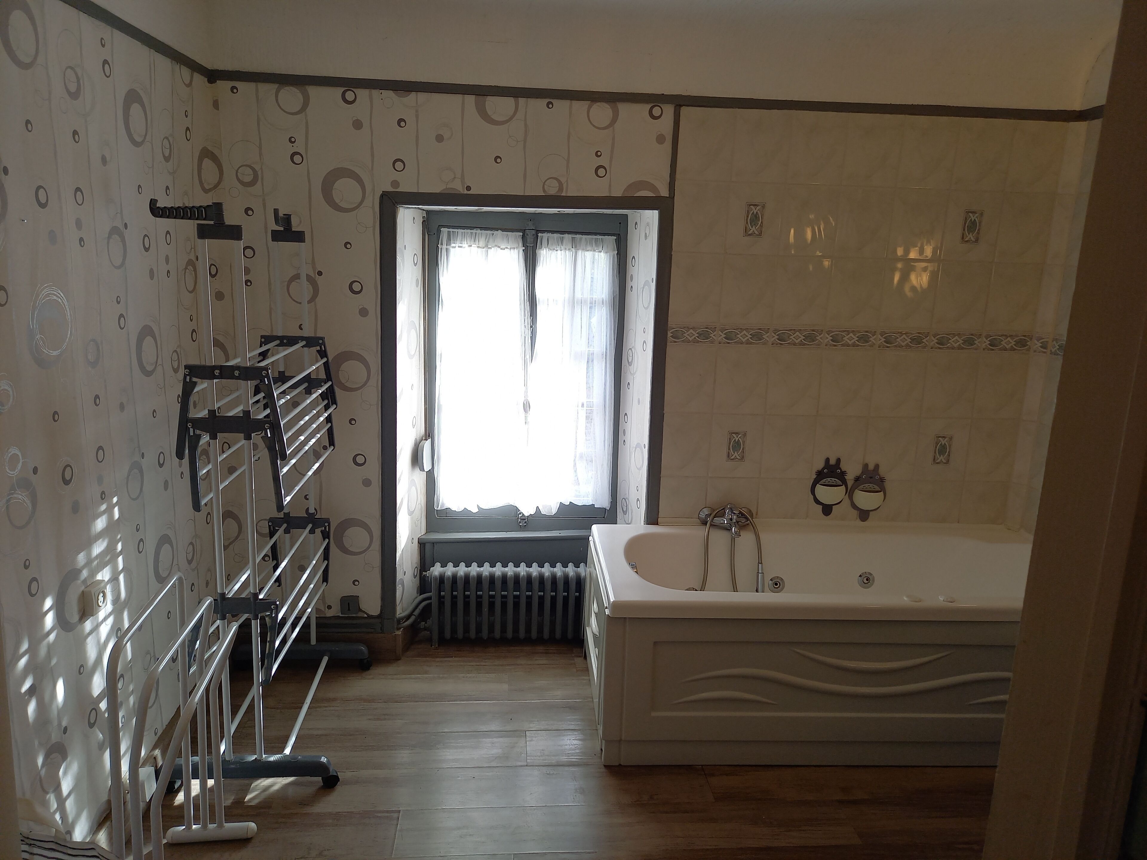 Un baño con bañera, un radiador, una ventana con cortinas y una zona de ducha.