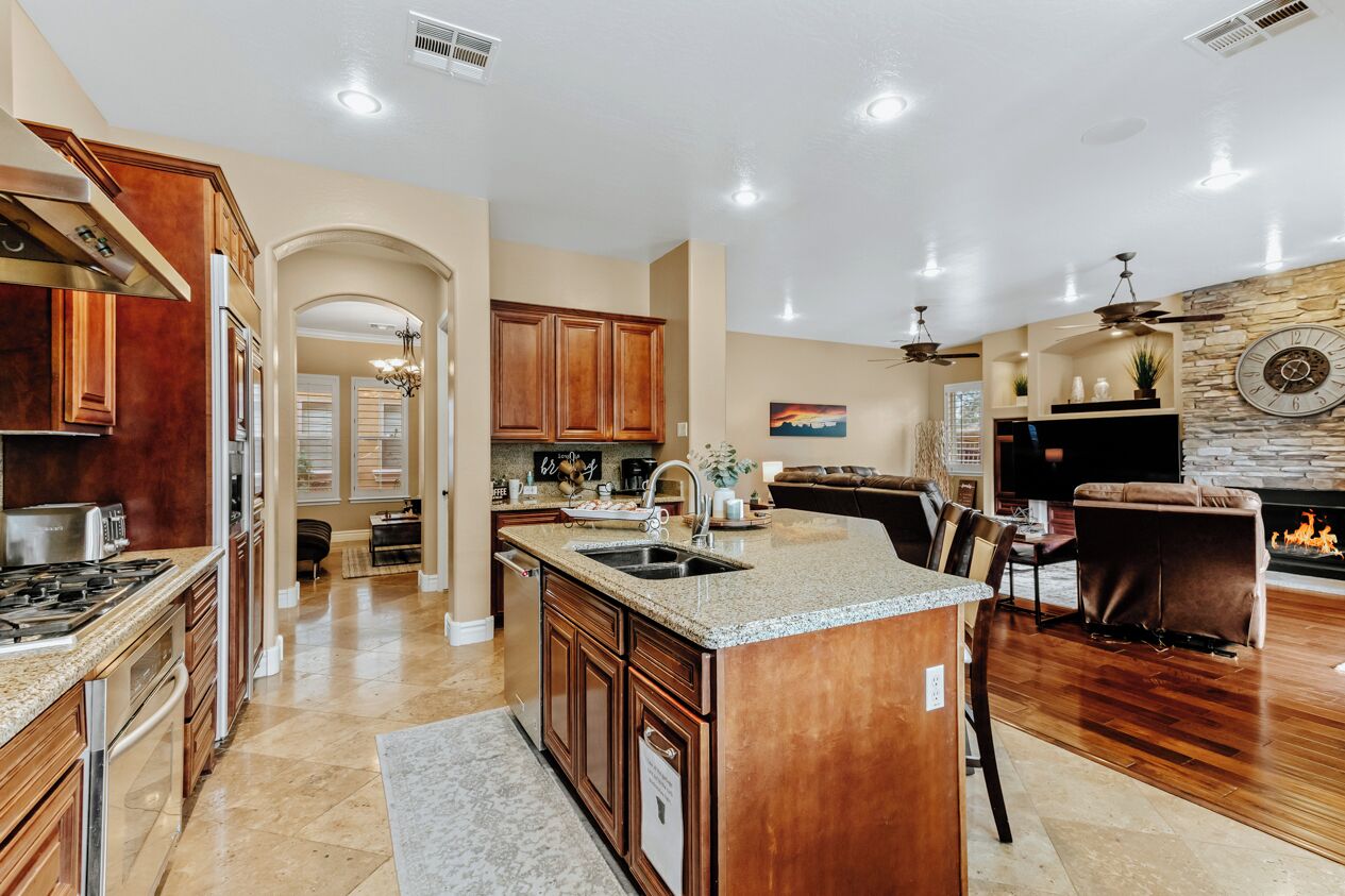 A spacious kitchen with granite countertops, wooden cabinets, and a central island.