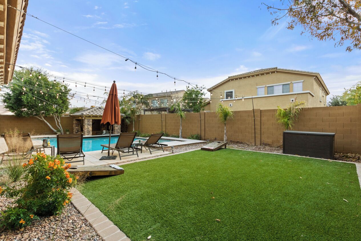 Un jardin avec une piscine, du mobilier d’extérieur et une pelouse bien entretenue.