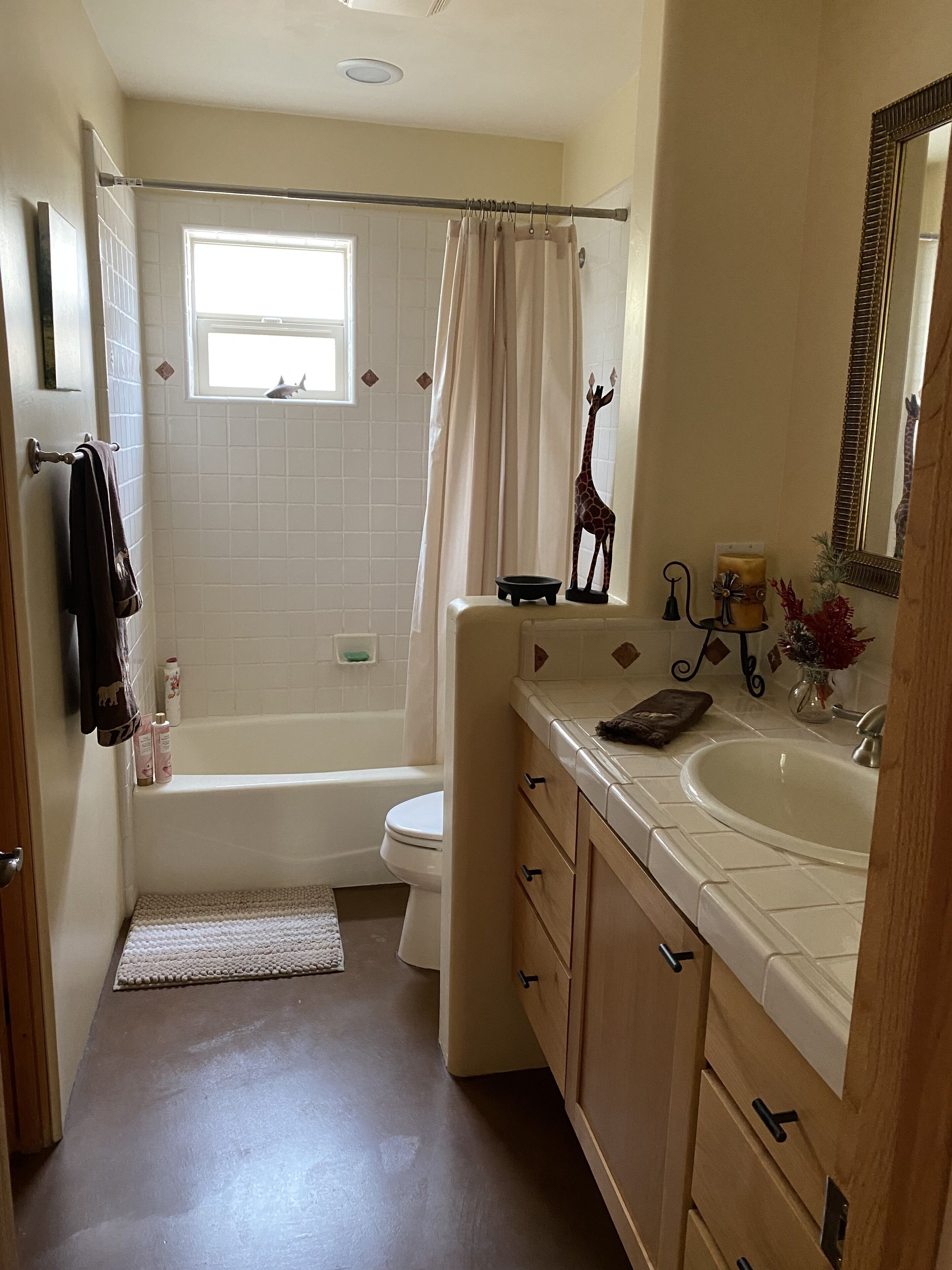 A bathroom with a bathtub, toilet, sink, and a window with a view of the outside.