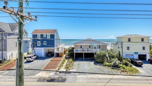 A coastal residential area with houses, a clear view of the ocean, and a street with vehicles. - Beach Bliss: 4br Beach Access Kayak Wi-fi 4 Bedroom Home by RedAwning (Holly Ridge)