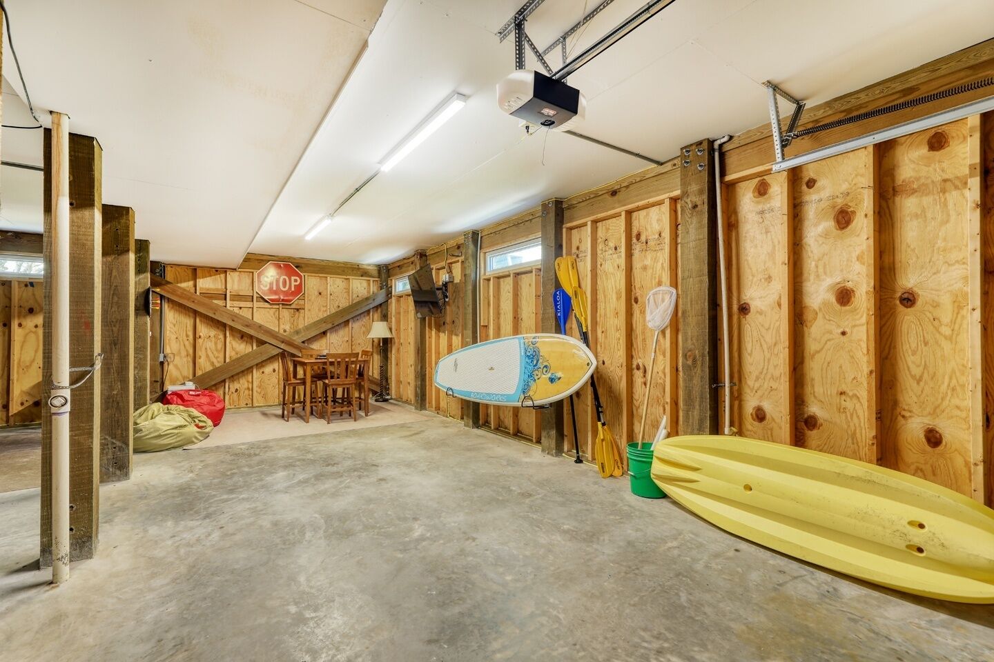 A garage with wooden walls, a concrete floor, a stop sign, and kayaks.