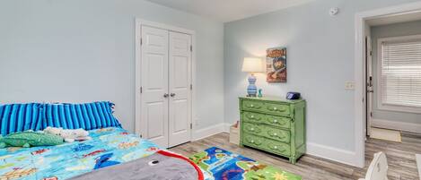 A bedroom with a bed, a dresser, a lamp, and a ceiling fan.