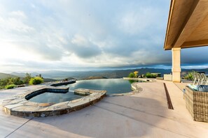 A hot tub area with a view of mountains and a cloudy sky.