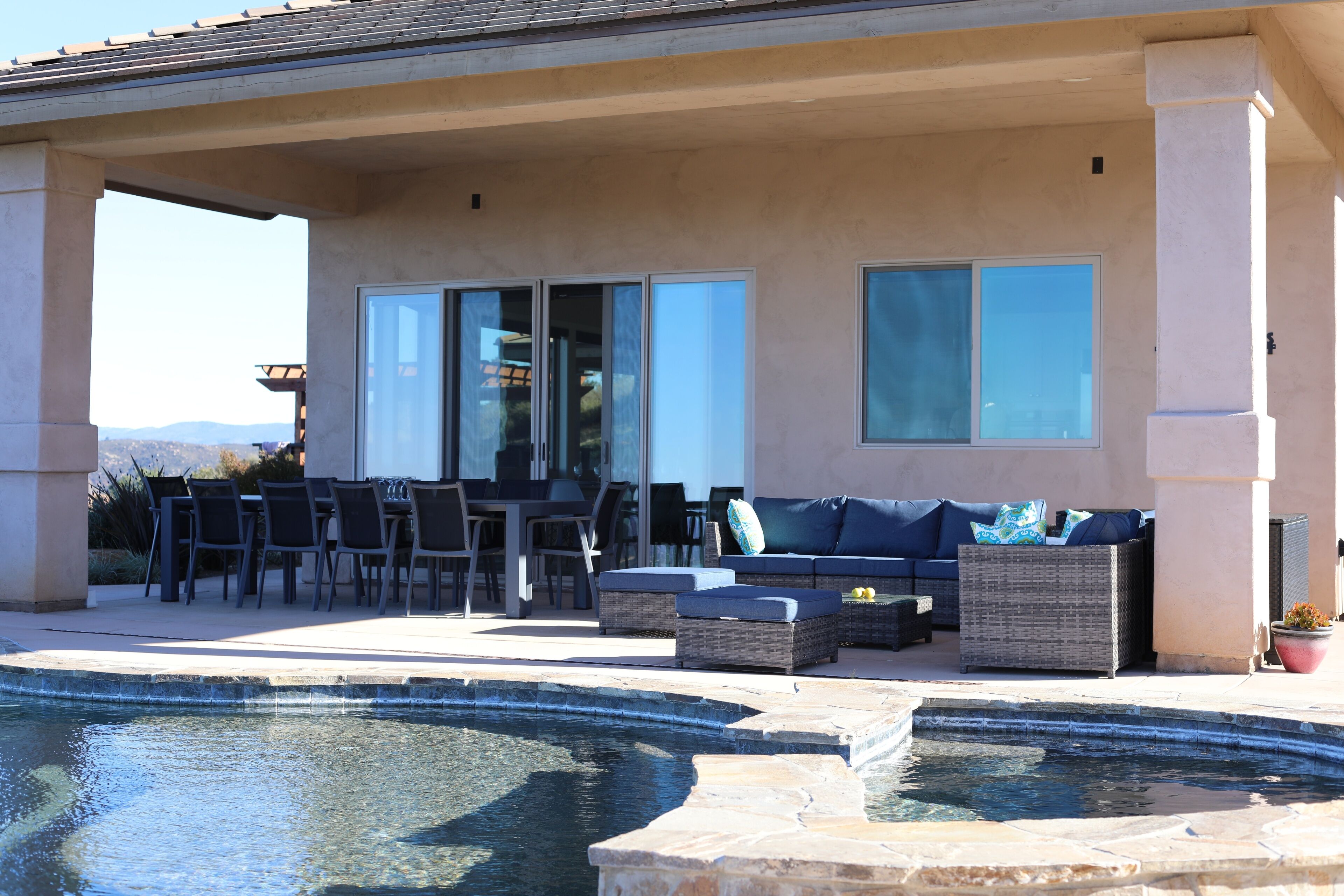 An outdoor patio with a pool, seating area, and a view of the mountains.