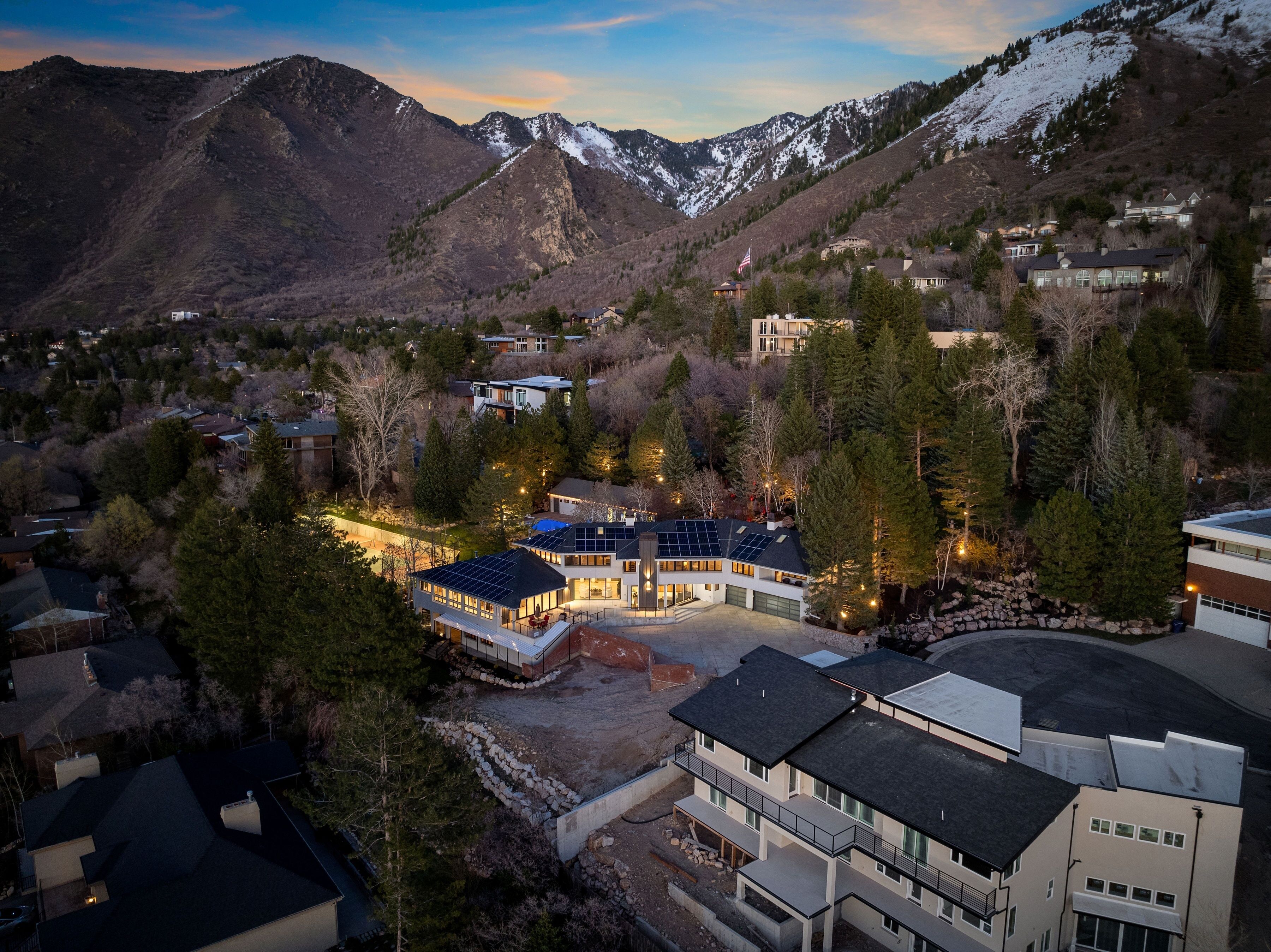 A modern residential area with houses, a large building with solar panels, and a mountainous backdrop.