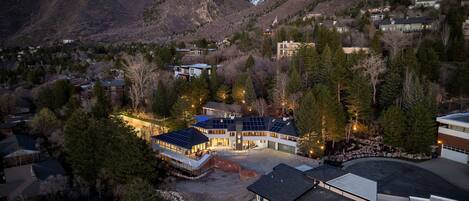 A modern residential area with houses, a large building with solar panels, and a mountainous backdrop.