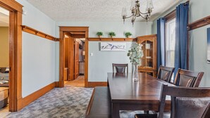 A dining room with a wooden table, chairs, and a chandelier. There is a bookshelf and a painting on the wall. - Niagara Falls Home 2BR, Pets OK, Free Parking (Niagara Falls)