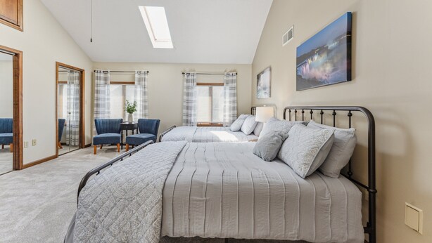 A bedroom with two beds, a skylight, a painting, and a view of a waterfall. - Niagara Falls Home 2BR, Pets OK, Free Parking (Niagara Falls)