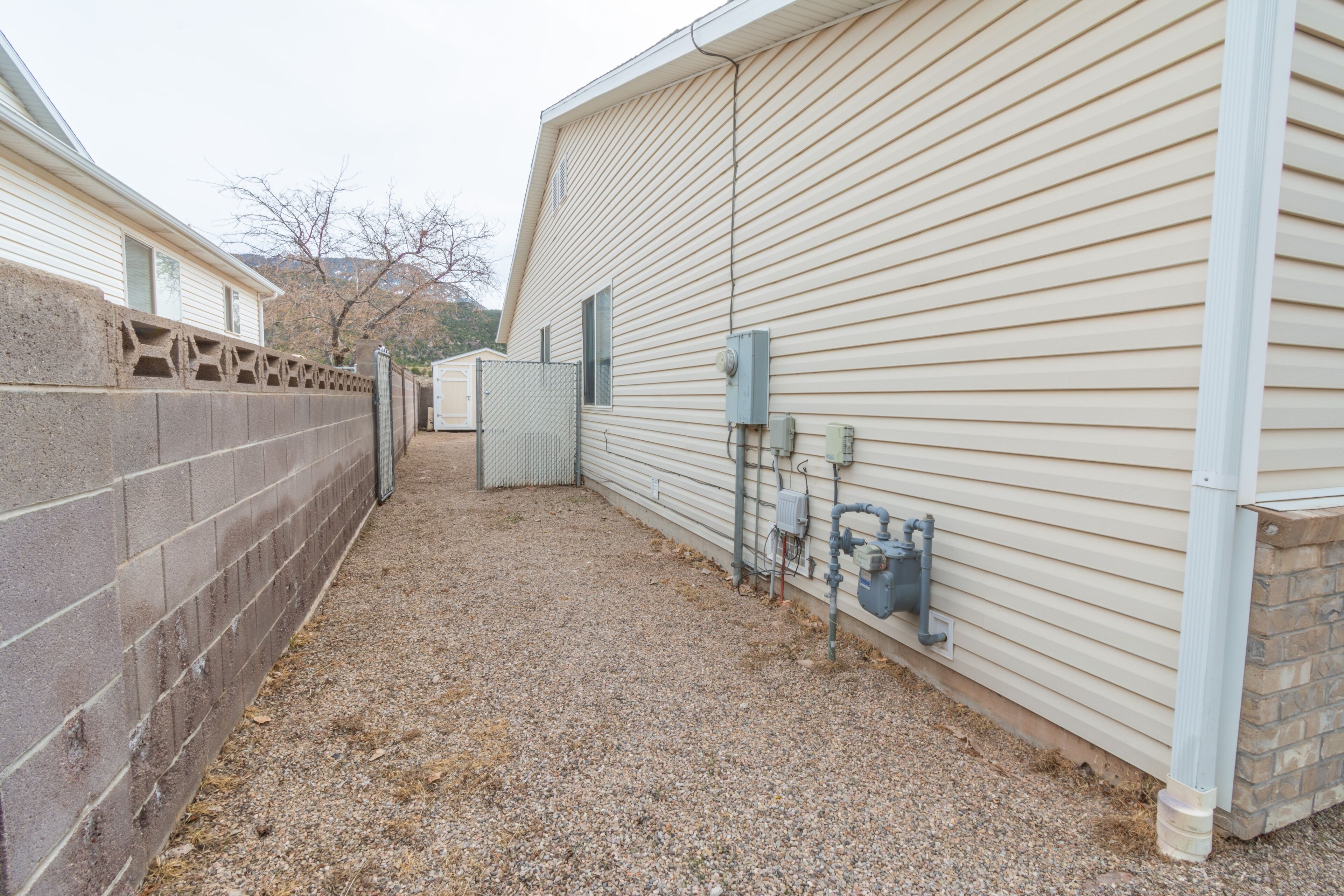 A building with a gravel driveway, a brick wall, and a metal fence.