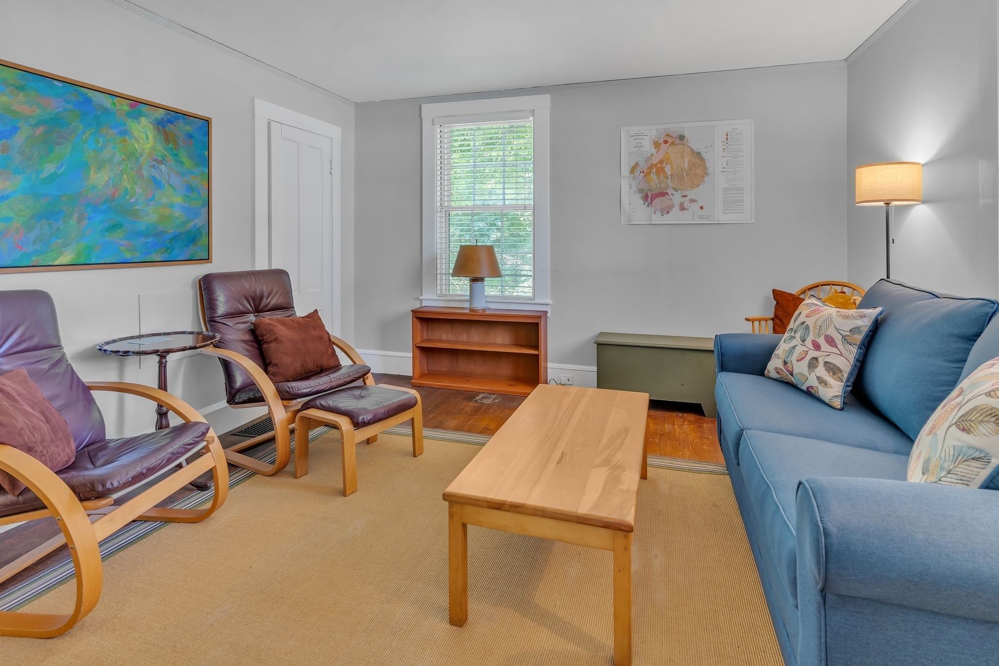 A living room with a blue sofa, leather armchairs, a wooden coffee table, and a map on the wall.