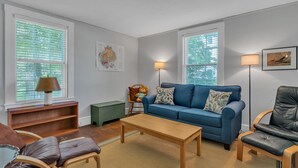 Un salon avec un canapé bleu, une table basse en bois et une petite table d’appoint verte.