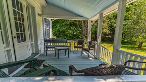 Une véranda avec une terrasse en bois, un banc, une table et des chaises.