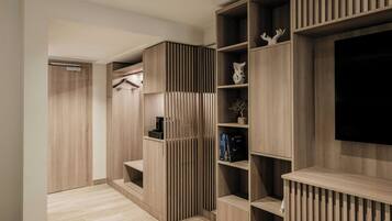 A modern interior with a built-in TV, wooden shelving, and a coat rack.