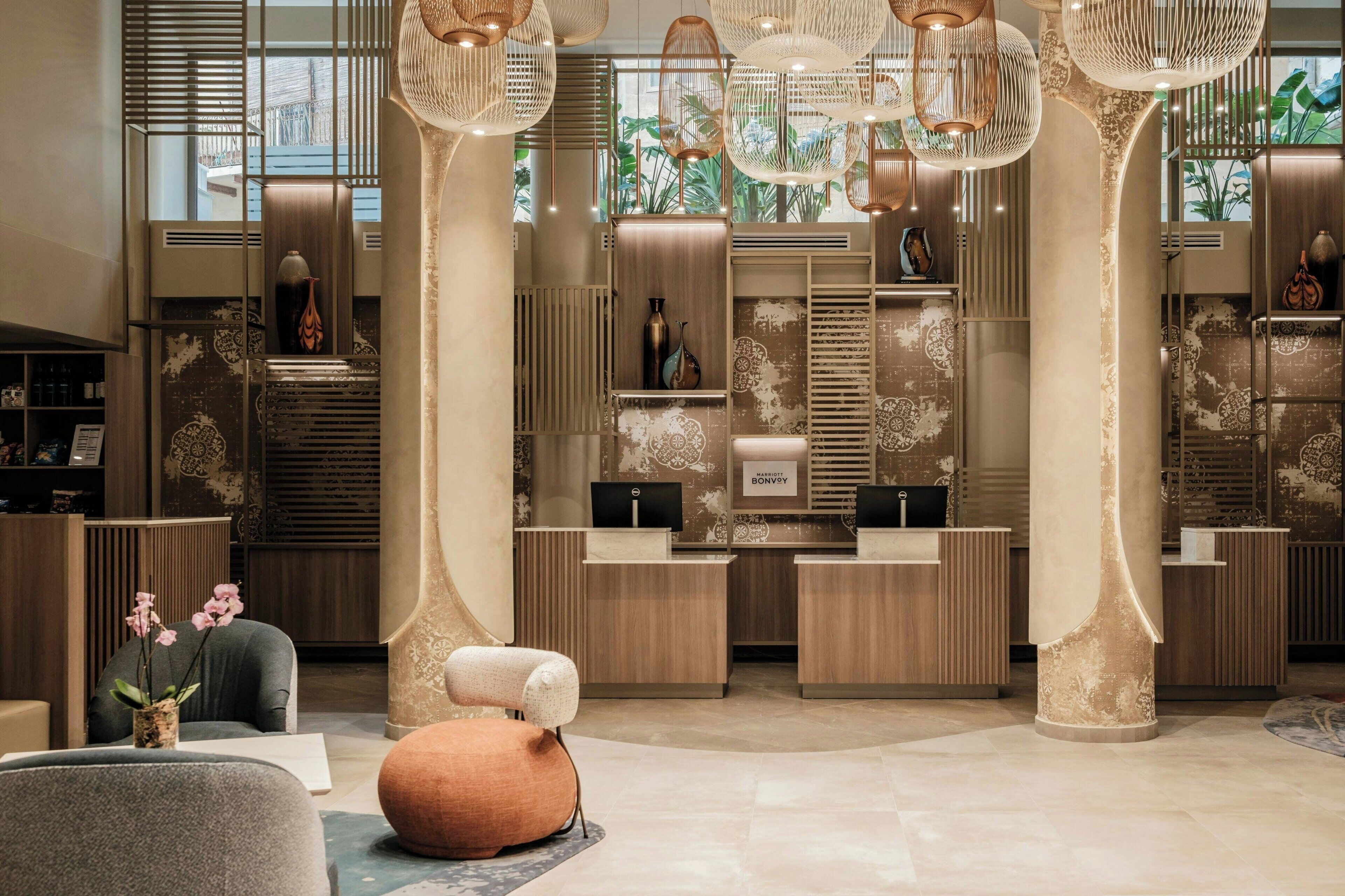 Una moderna zona de recepción con un mostrador central, columnas decorativas e lámparas colgantes.