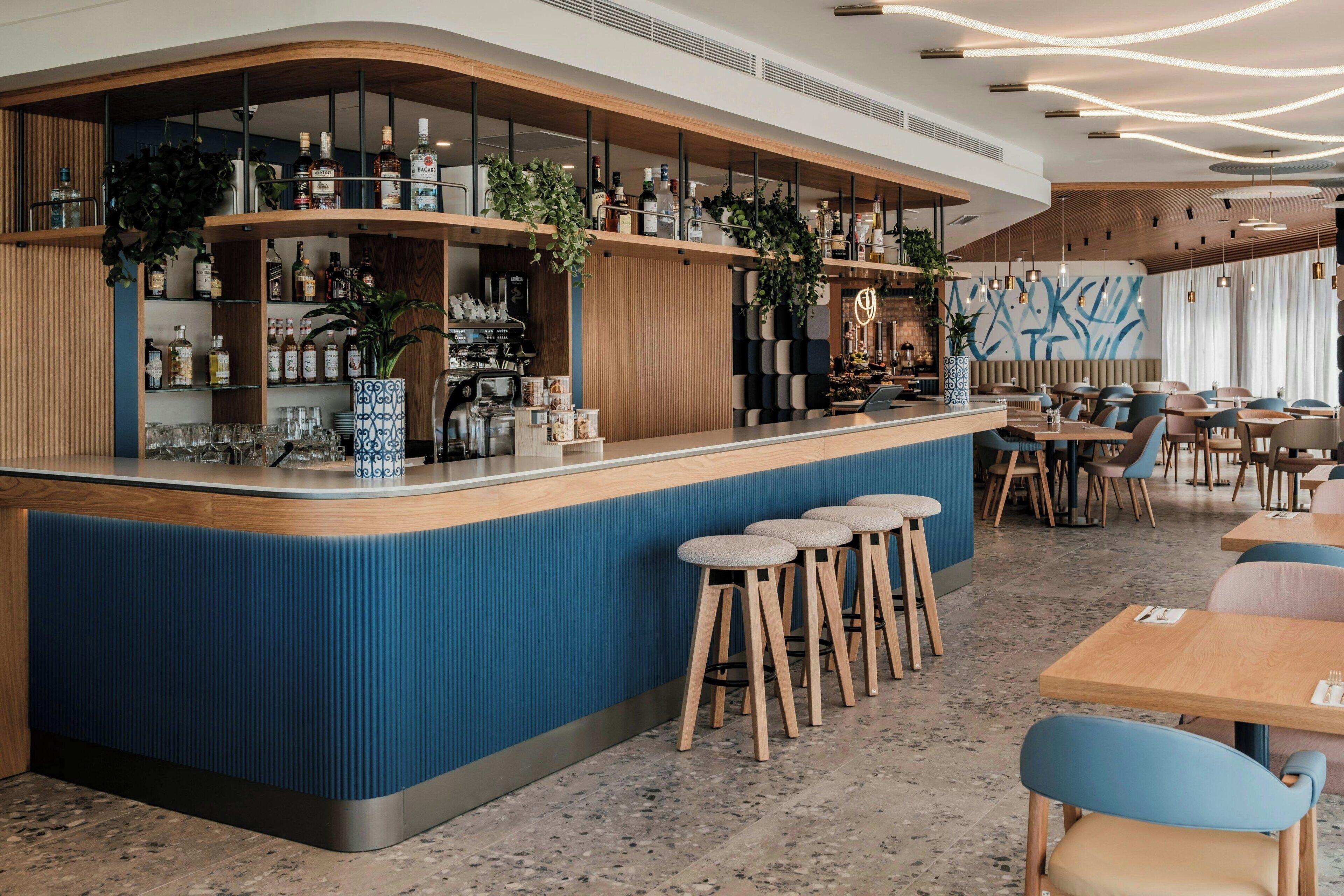 A modern bar area with a curved counter, stools, and seating.