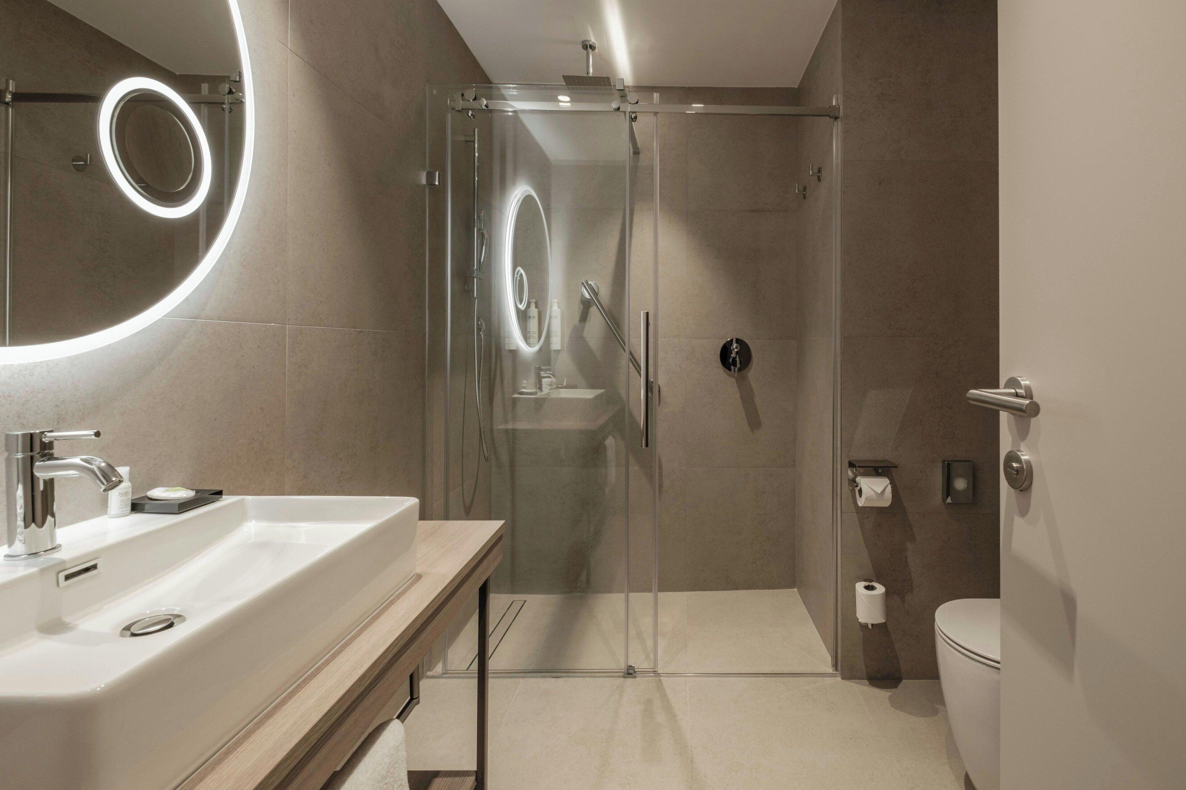 Une salle de bain moderne avec une douche à parois de verre, un lavabo avec un miroir et des toilettes.