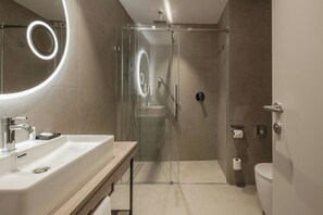 A modern bathroom with a glass-enclosed shower, a sink with a mirror, and a toilet.