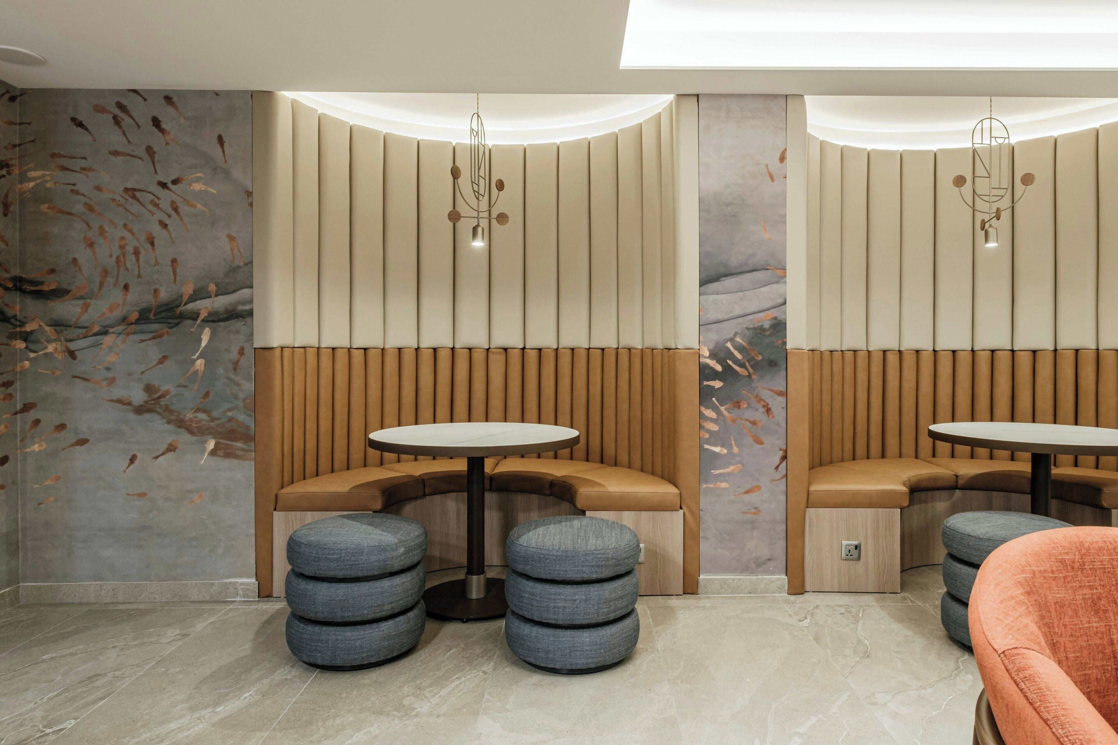 A modern interior with a curved seating area, round tables, and a decorative wall with abstract patterns.