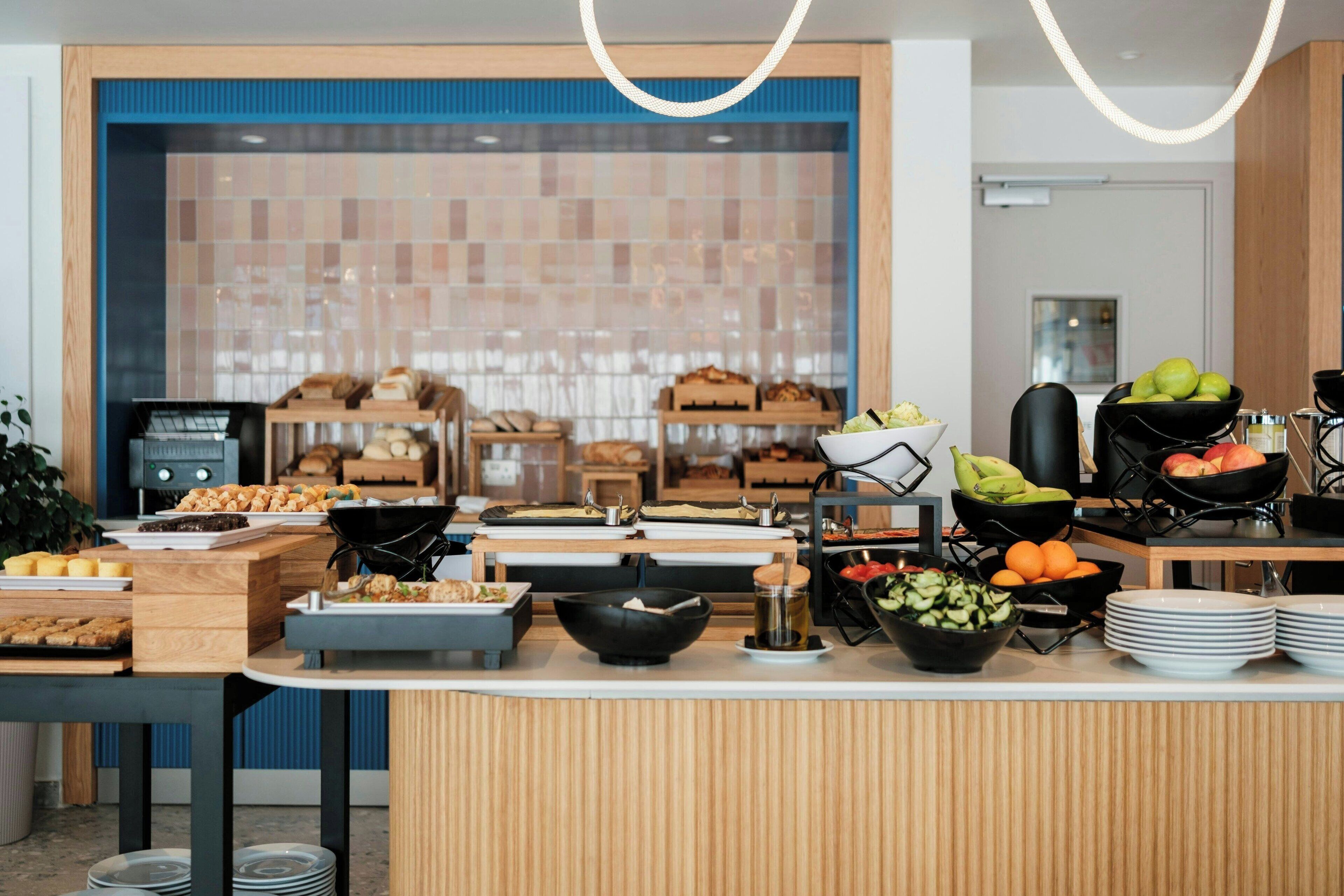 A buffet setup with various food items and a kitchen area in the background.