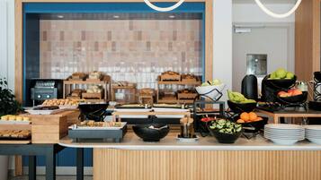 A buffet setup with various food items and a kitchen area in the background.
