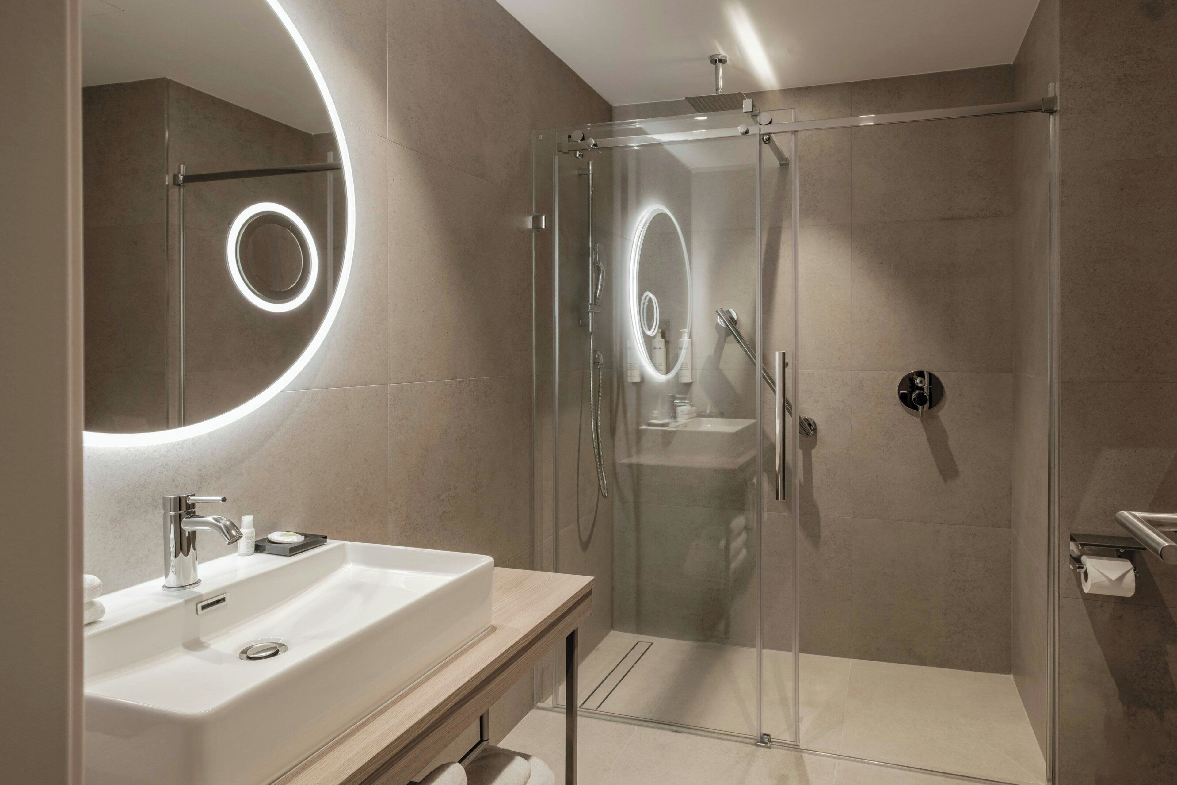 Un bagno moderno con doccia vetro, lavabo con specchio e servizi igienici.