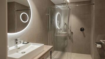 Un bagno moderno con doccia vetro, lavabo con specchio e servizi igienici.