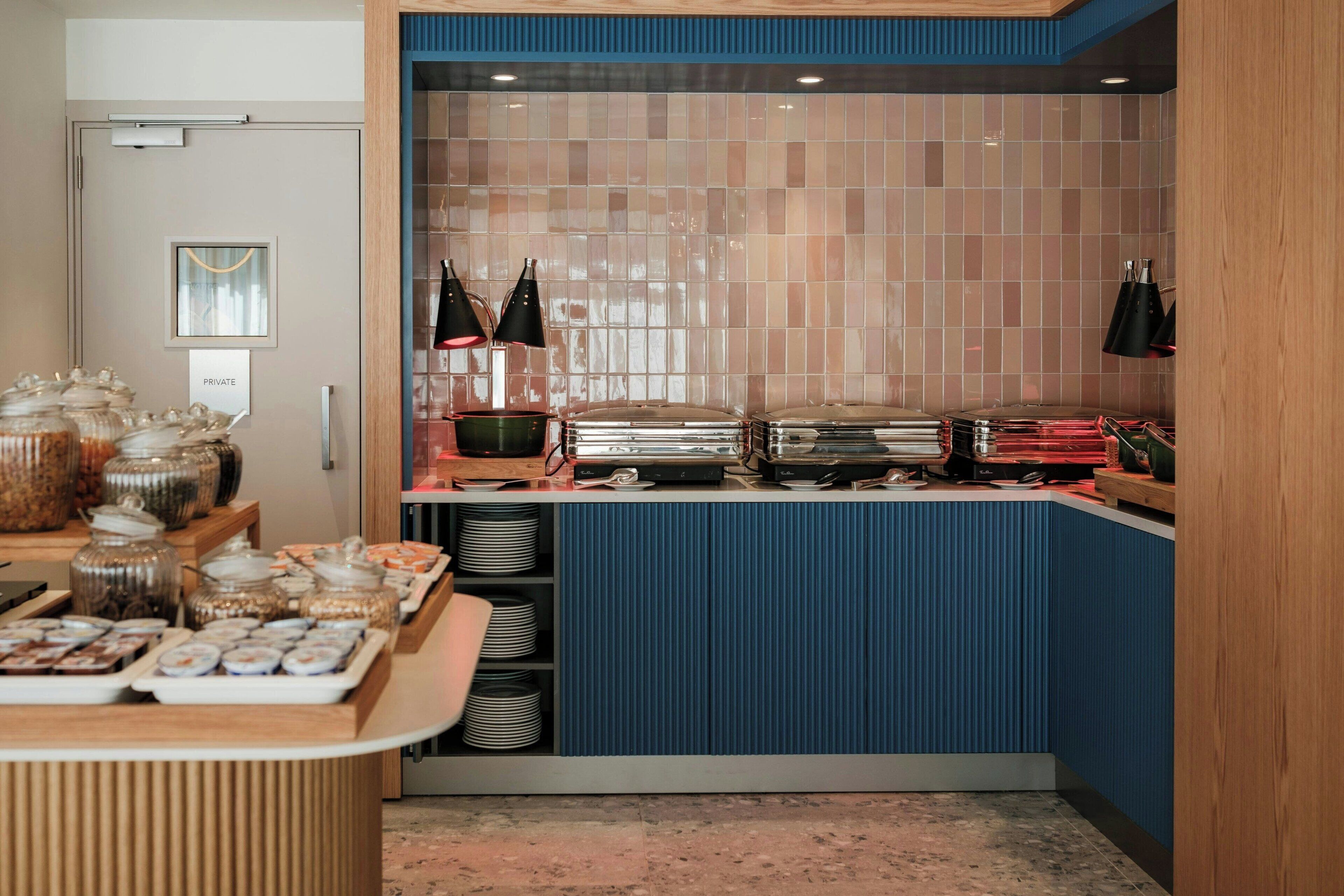 A kitchenette with a blue accent wall, a private door, and various food items on the counter.