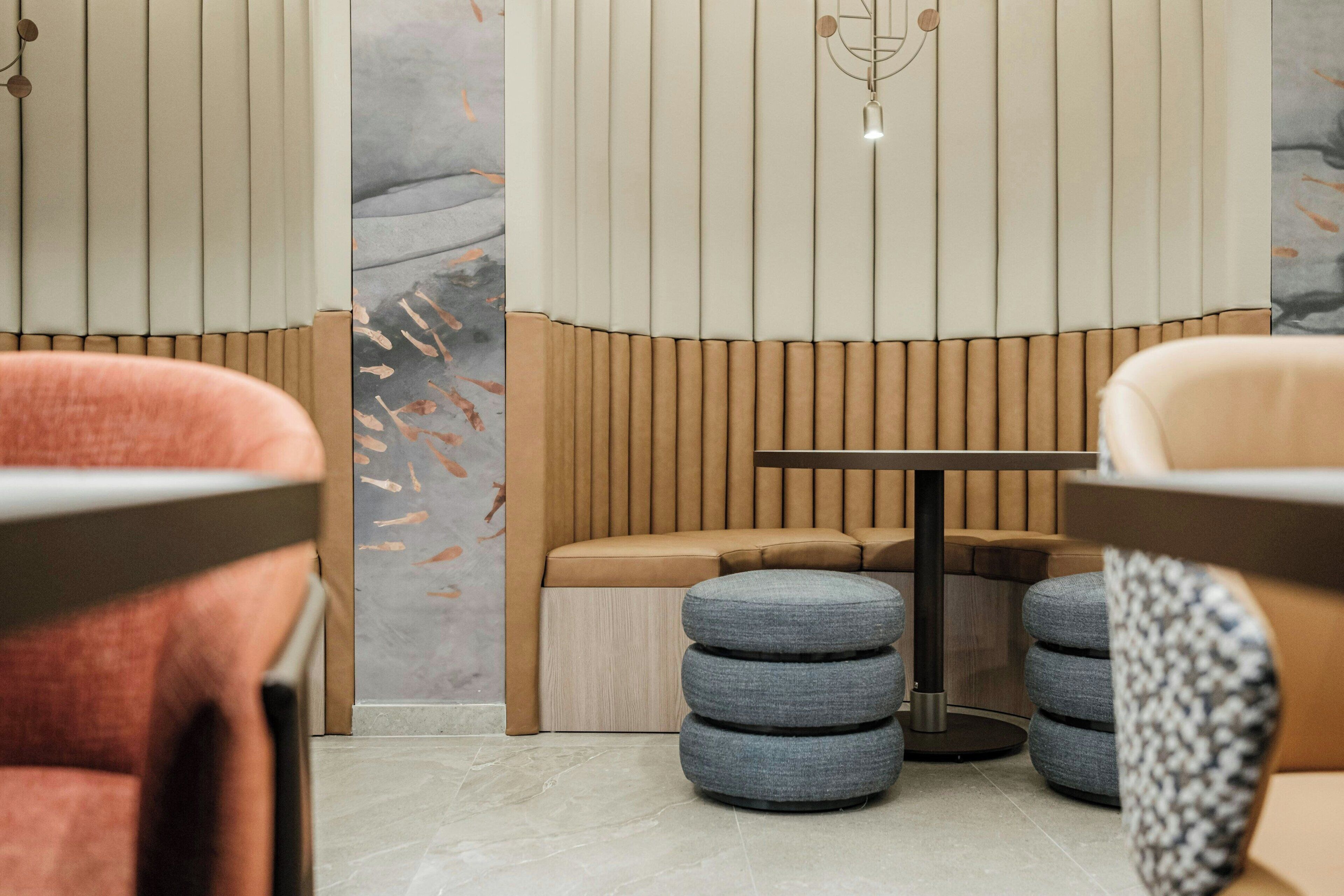 A modern interior with a sofa, ottomans, and a table.