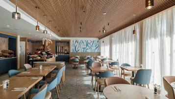 Un restaurante moderno con paneles de techo de madera, sillas azules y una zona de bar.