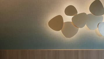A wall with a textured surface and a wooden panel at the bottom.