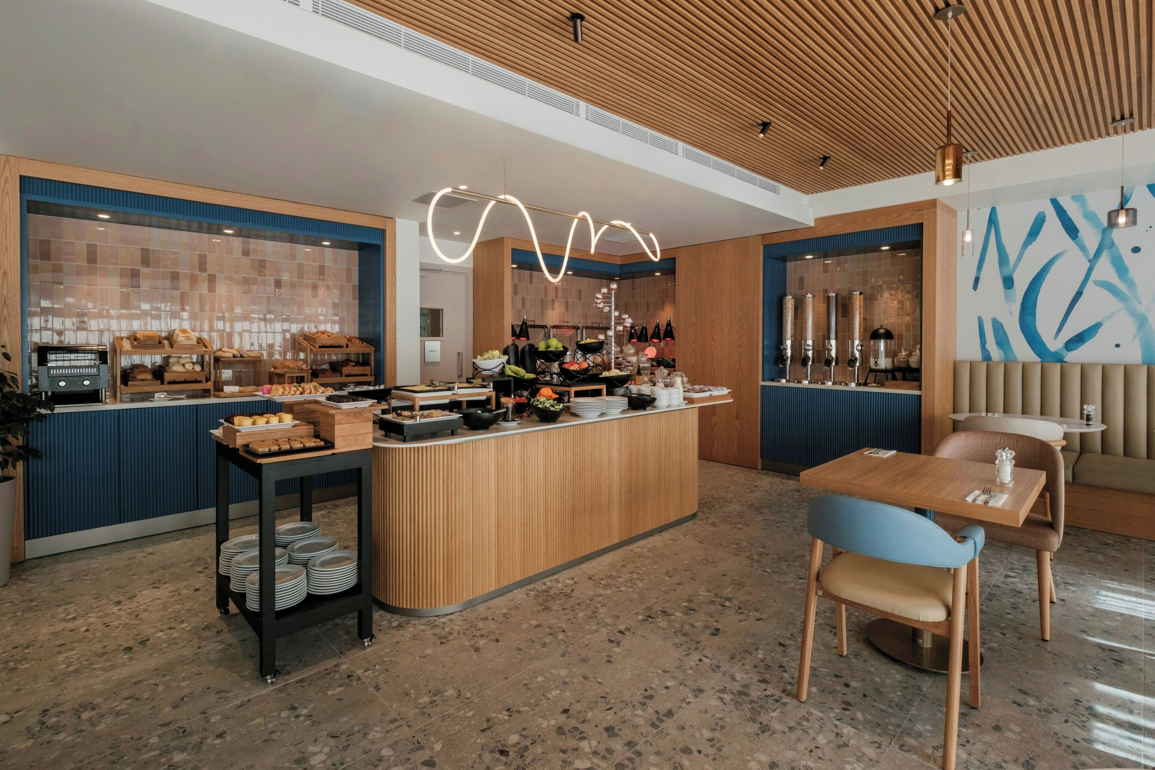 Un café moderno con mostrador de madera, zona de estar y una lámpara decorativa.