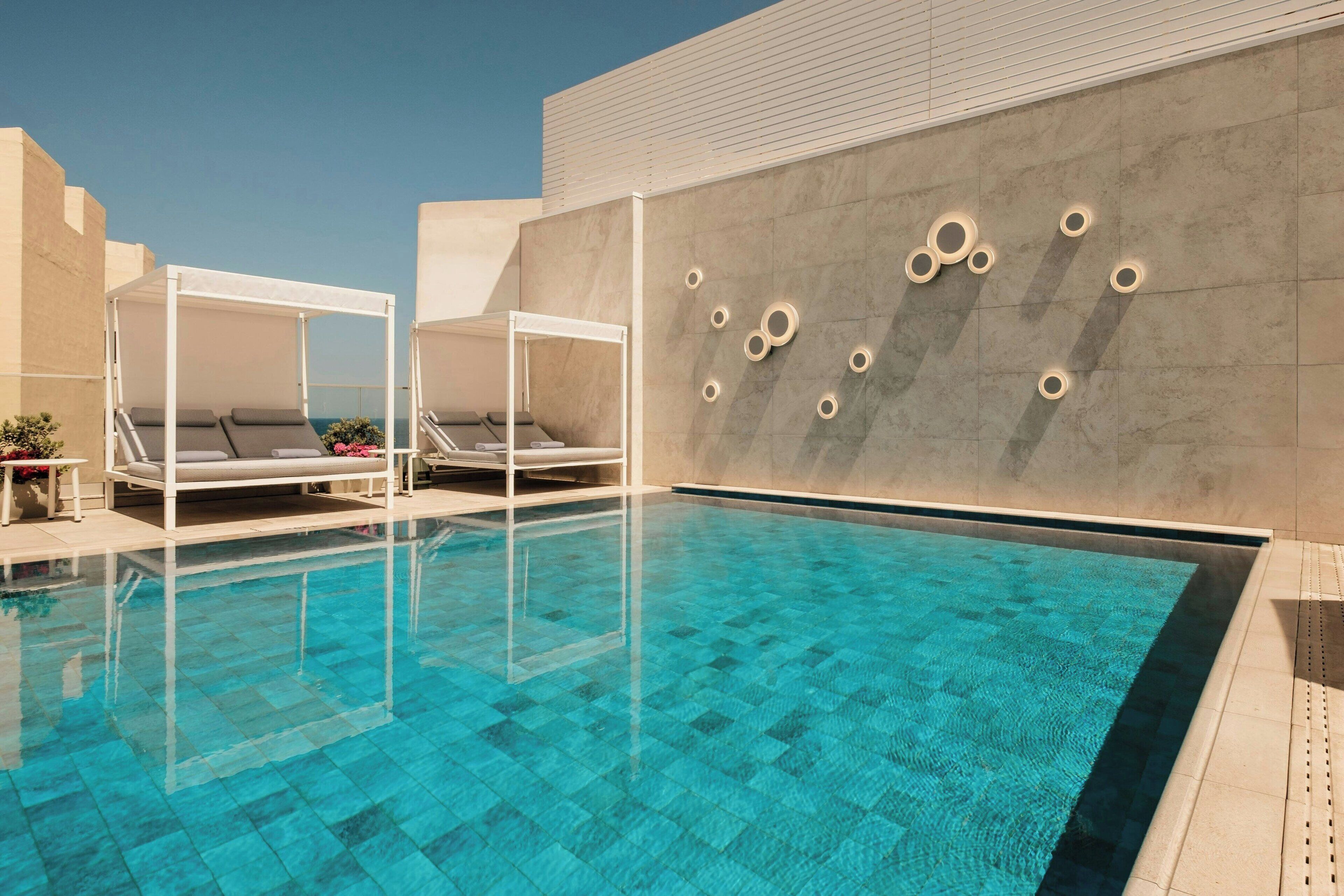 Ein Pool mit Liegestühlen und einer Wand mit kreisförmigen Mustern.