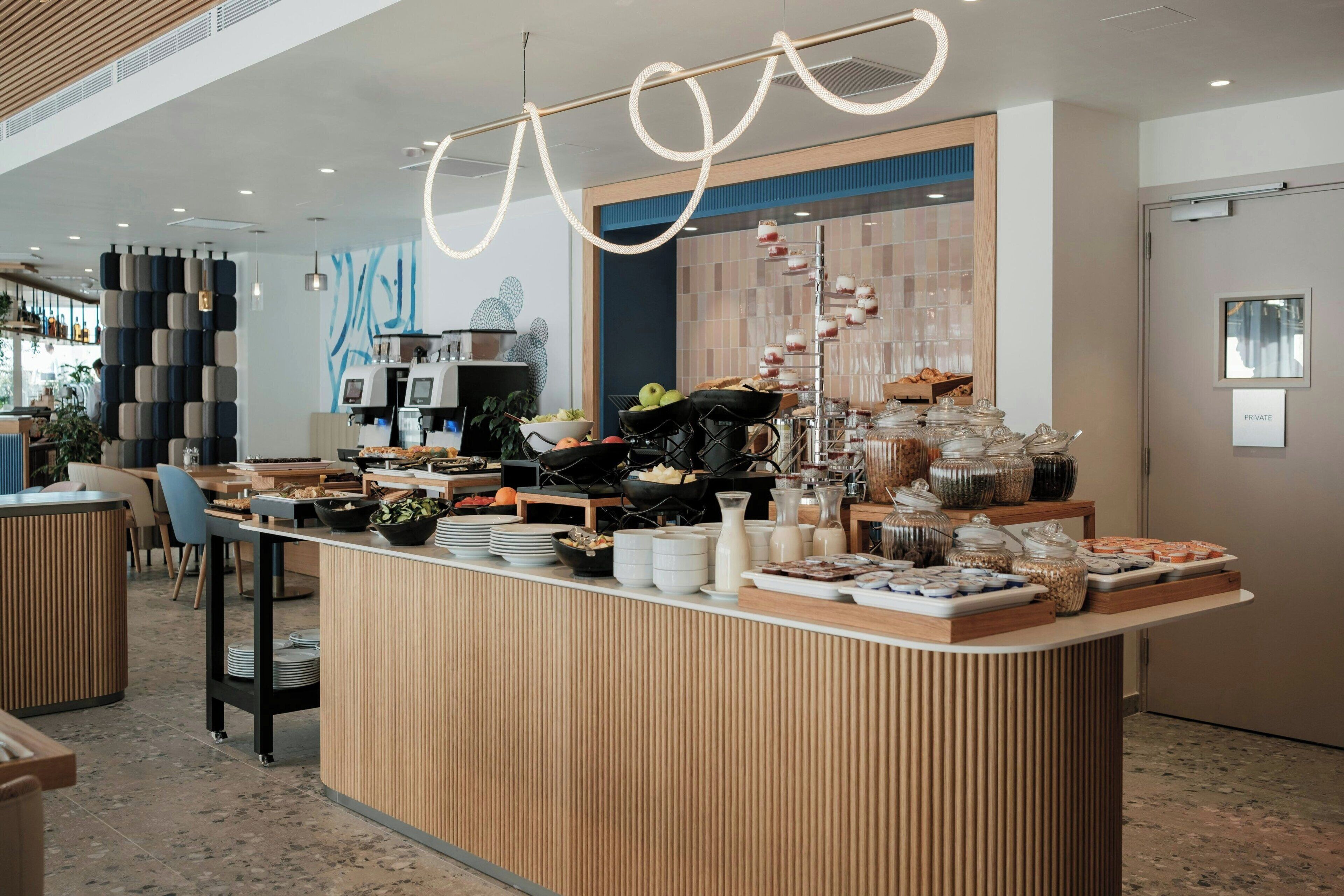 A modern breakfast bar with a variety of food items and beverages, a private room sign, and a contemporary interior design.