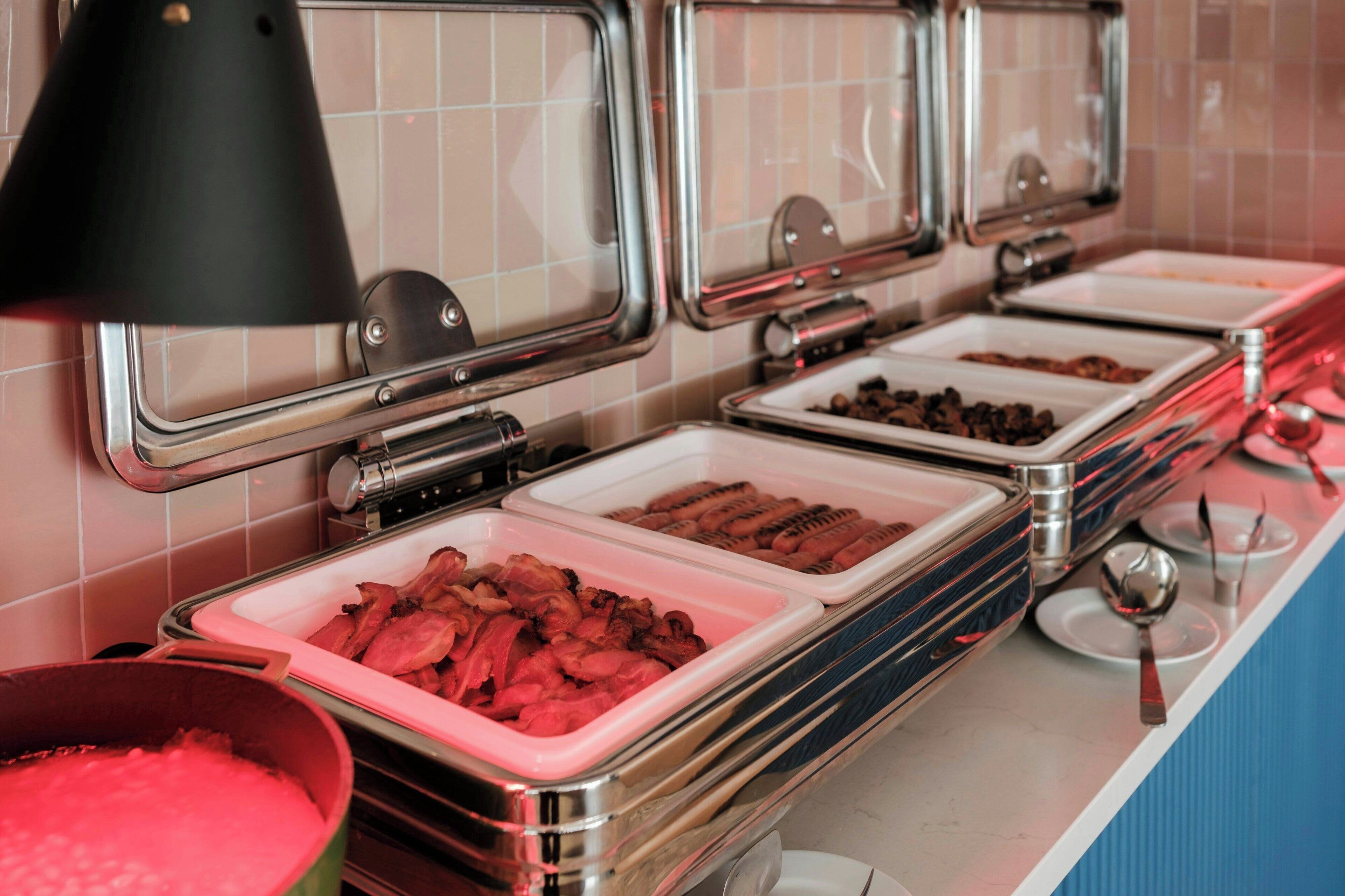 A buffet with multiple serving trays containing various food items.