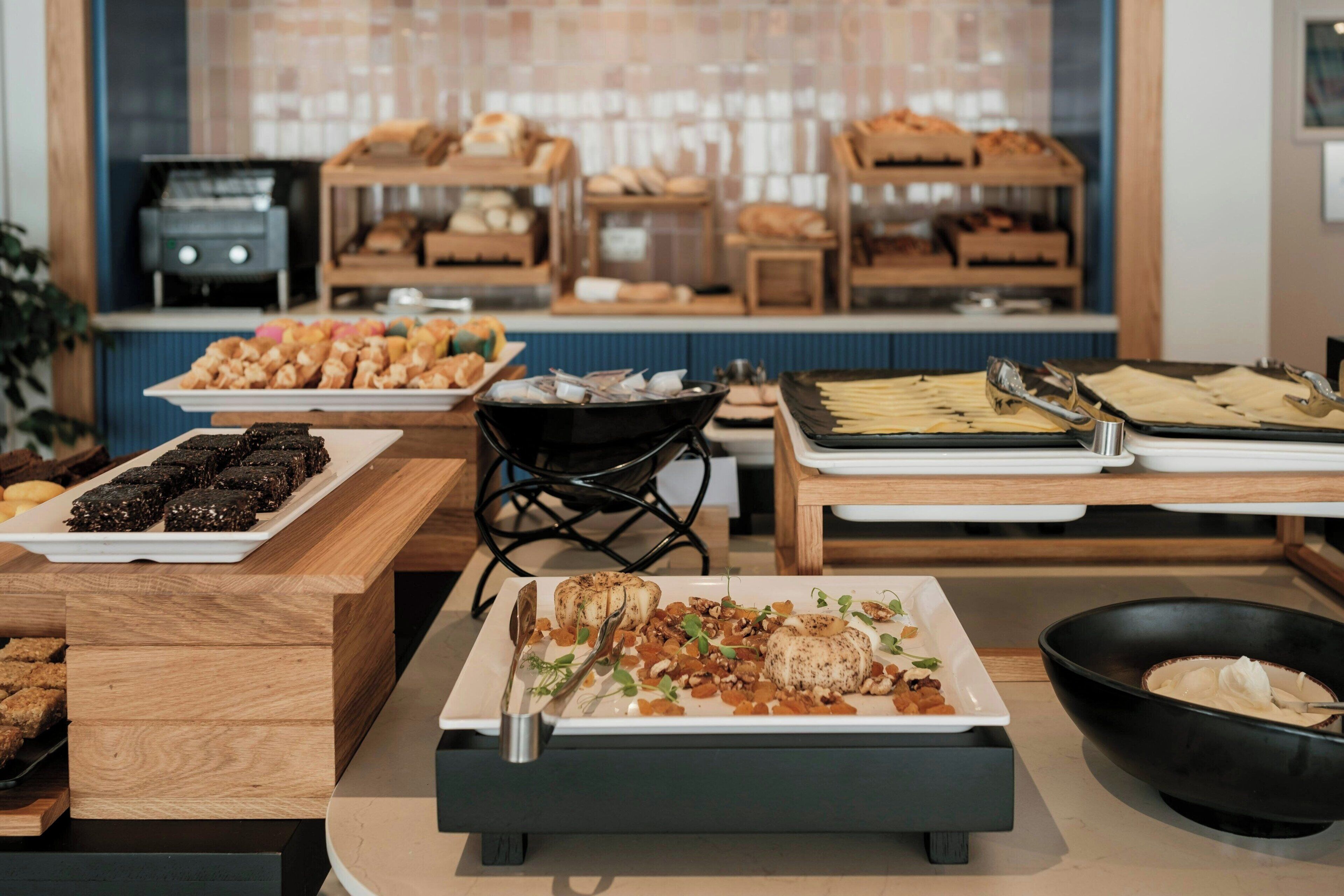A buffet setup with various food items including sushi, pastries, and a roasted chicken dish.