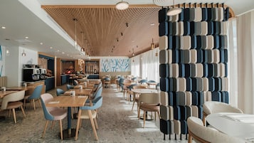 Un restaurante espacioso con paneles de techo de madera, sillas modernas y un papel tapiz decorativo.