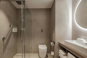 Enjoy a serene bathroom experience with a glass-enclosed shower, standalone toilet, and spacious vanity.