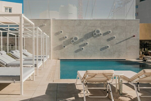 Relax by the pool surrounded by lounge chairs and sunbeds.