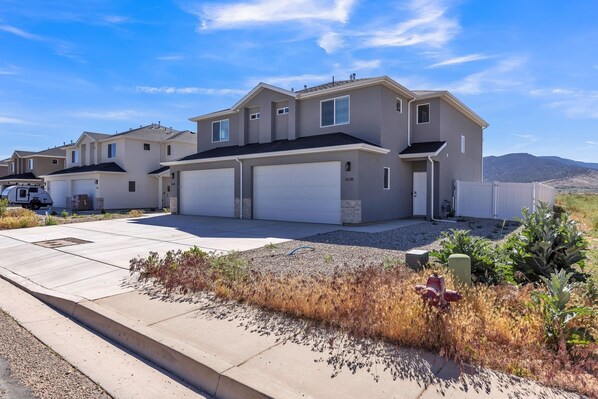 A modern two-story residential building with a garage, a driveway, and a well-maintained lawn.
