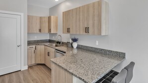 A modern kitchen with light wood cabinets, granite countertops, and stainless steel appliances. - The Ideal Getaway 3 Bedroom Home by RedAwning (Cedar City)