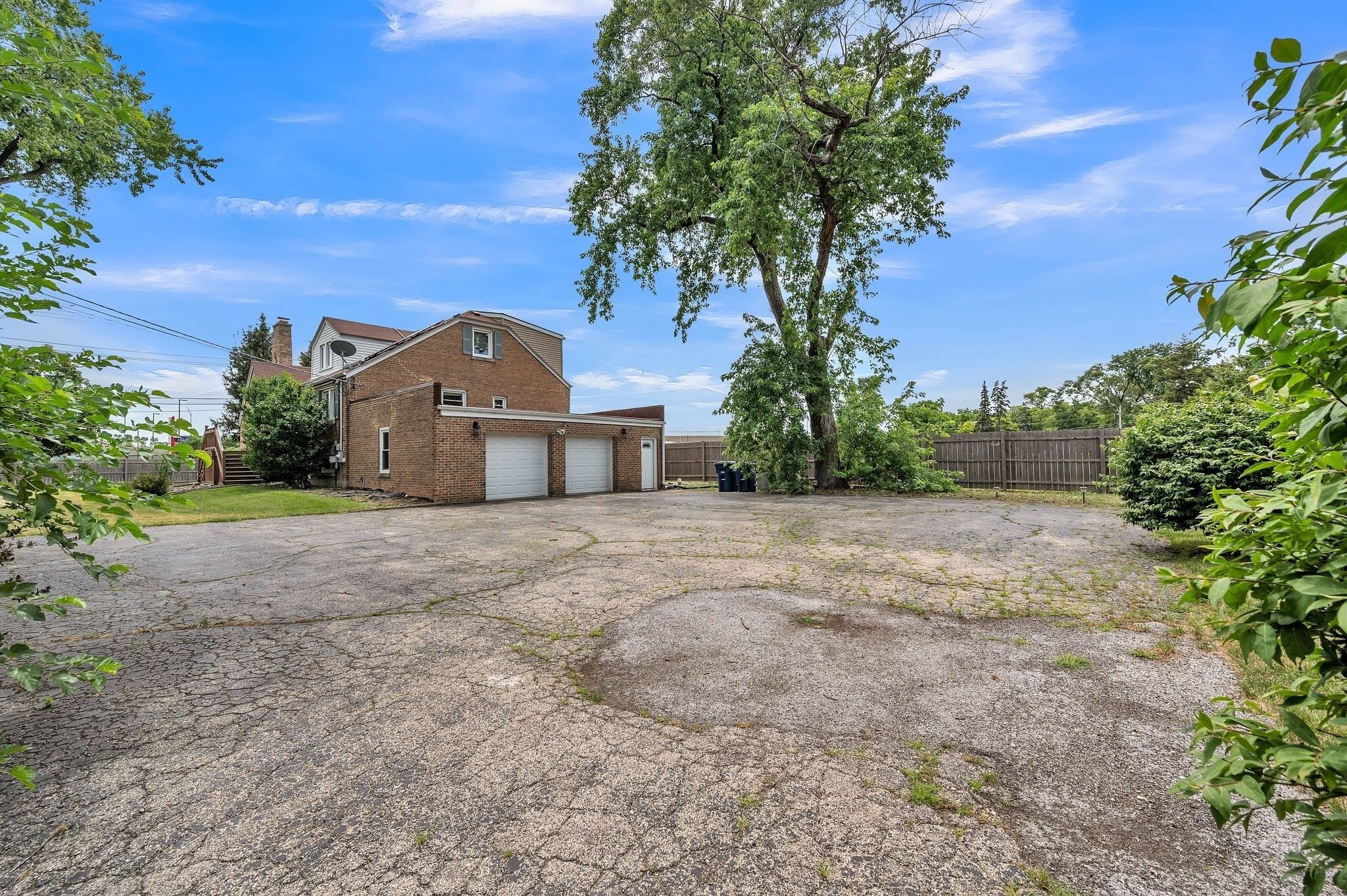 A residential property with a garage, a brick house, and a large driveway.