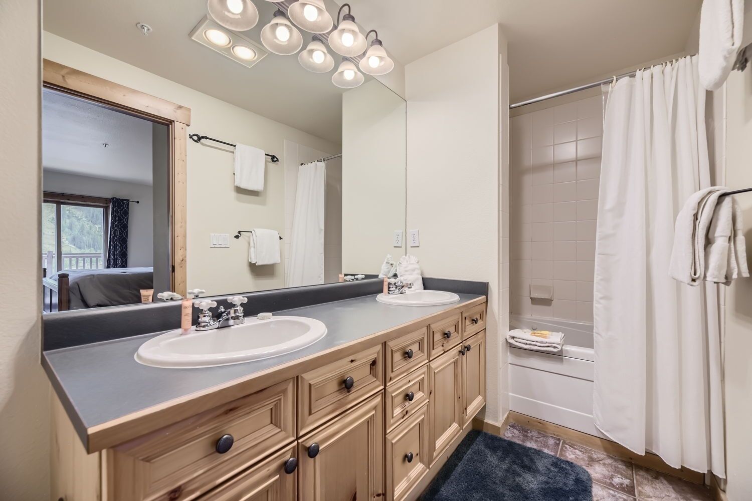 A bathroom with two sinks, a large mirror, and a shower area.