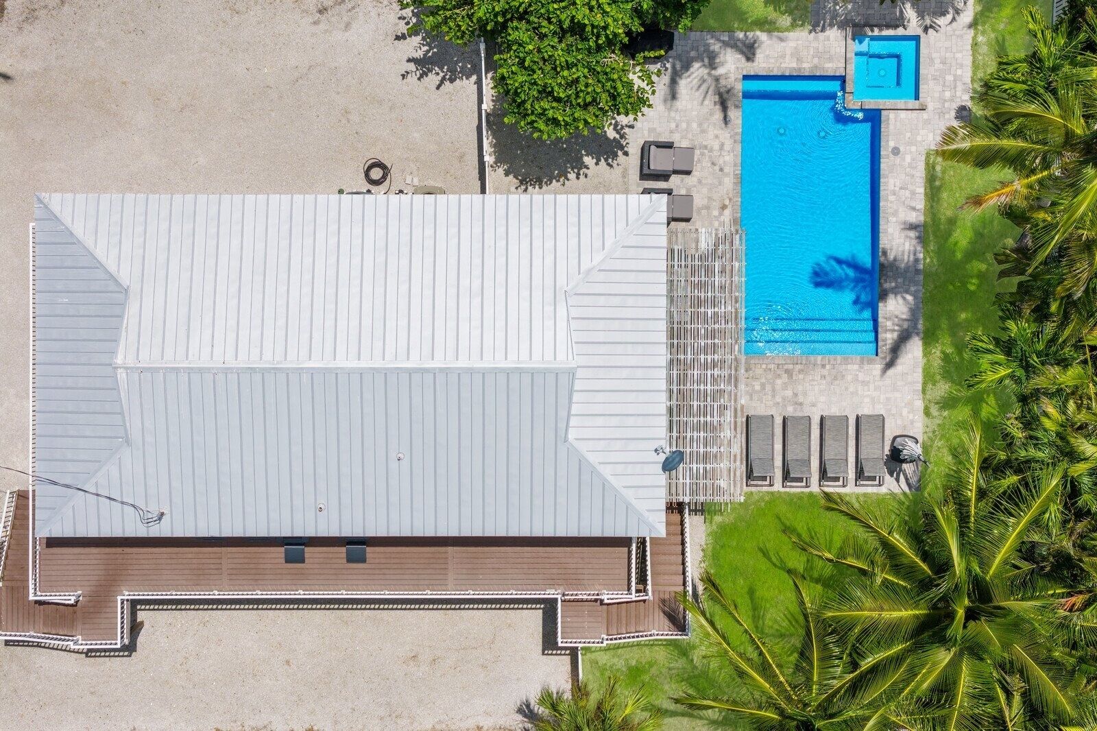 An aerial view of a building with a flat roof, a swimming pool, and a patio area with lounge chairs.