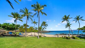 A tropical beach setting with palm trees, a clear blue sky, and a view of the ocean. - Big Island Golf Villas A1 3 Bedroom Condo (Kamuela)
