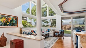 A spacious living area with large windows, a wooden floor, and a view of the outdoors. - Big Island Golf Villas A1 3 Bedroom Condo (Kamuela)