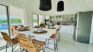 A modern kitchen with a central island, white cabinetry, and a stainless steel refrigerator. - Charming spacious 3-bedroom villa with panoramic views of Orient Bay Beach.

 (Mont Vernon)