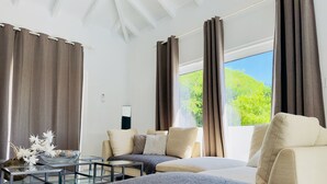 A modern living room with a sofa, armchairs, a glass coffee table, and a view of greenery outside. - Charming spacious 3-bedroom villa with panoramic views of Orient Bay Beach.

 (Mont Vernon)